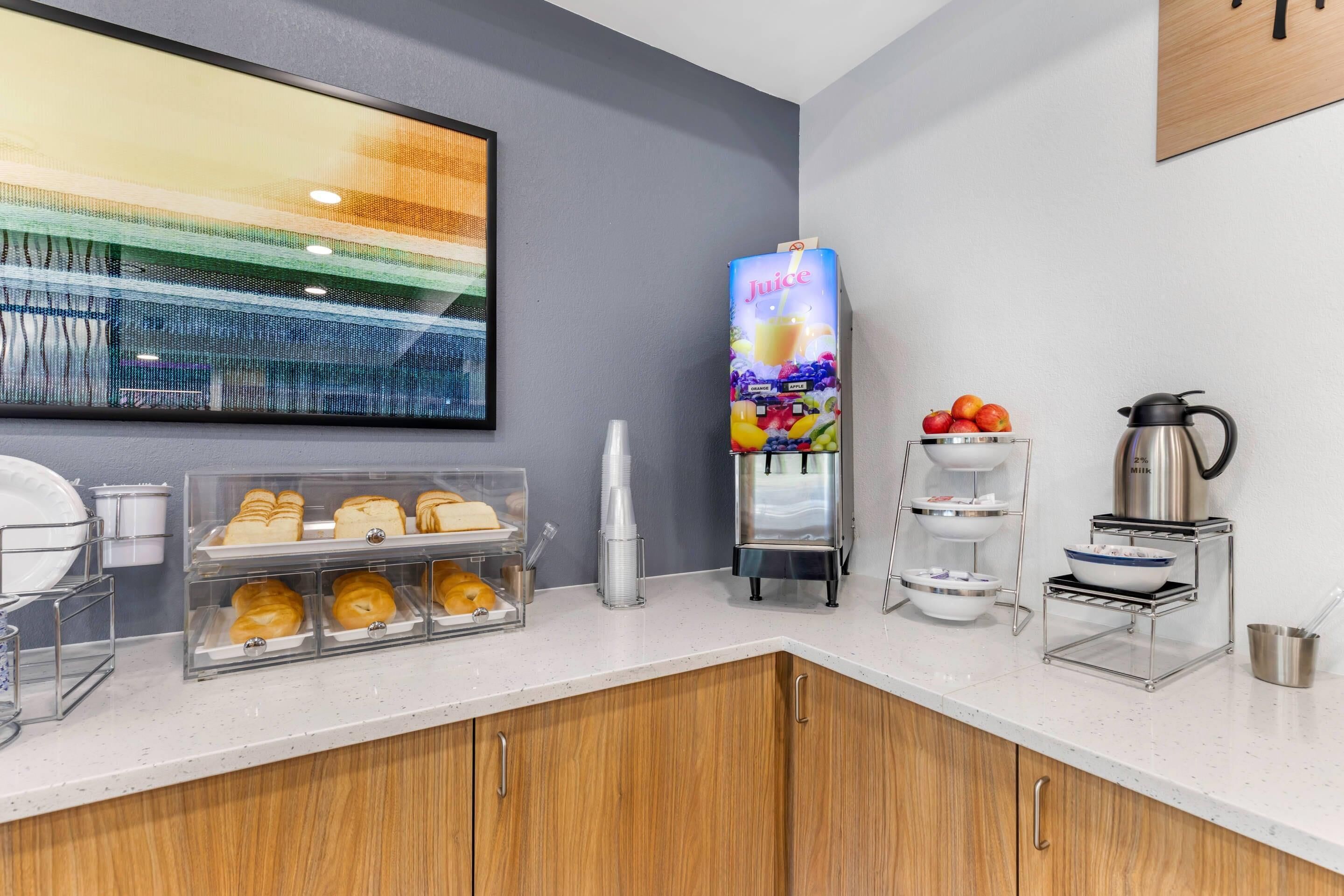 A breakfast bar with pastries, a juice dispenser, and a coffee maker.