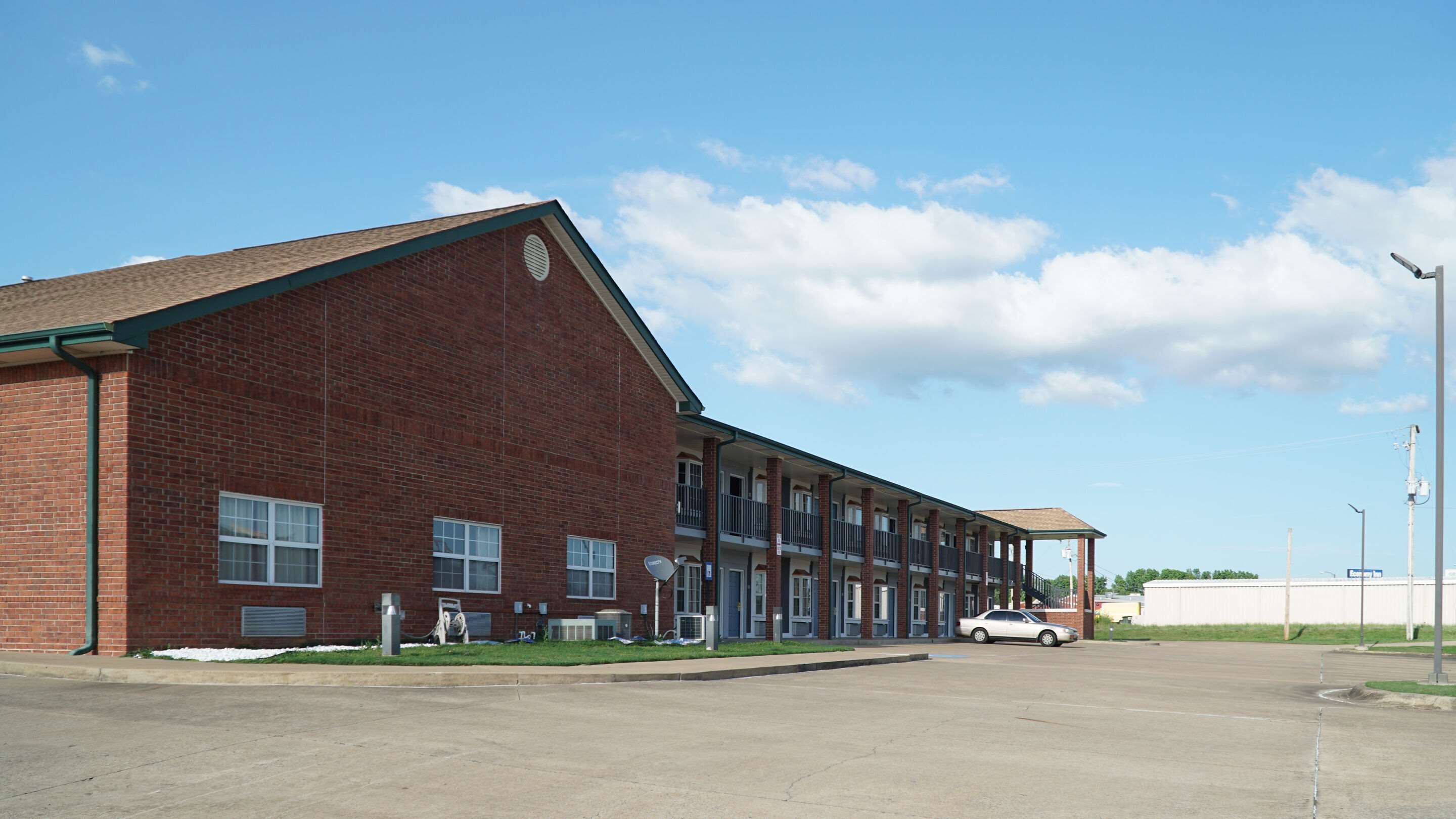 A multi-story brick building with a flat roof, large windows, and a covered parking area.