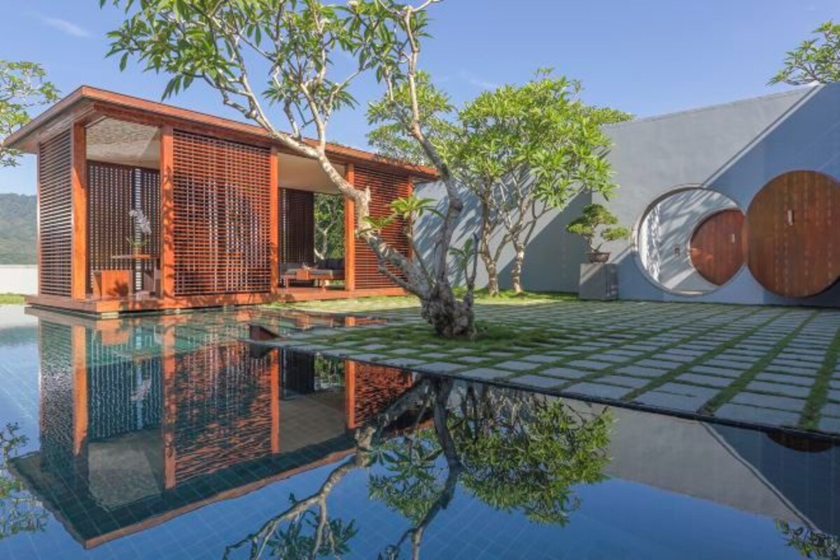 A modern building with a pool, a tree, and a circular design element.