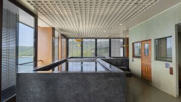 A modern interior with a large central water feature, large windows, and a patterned ceiling.