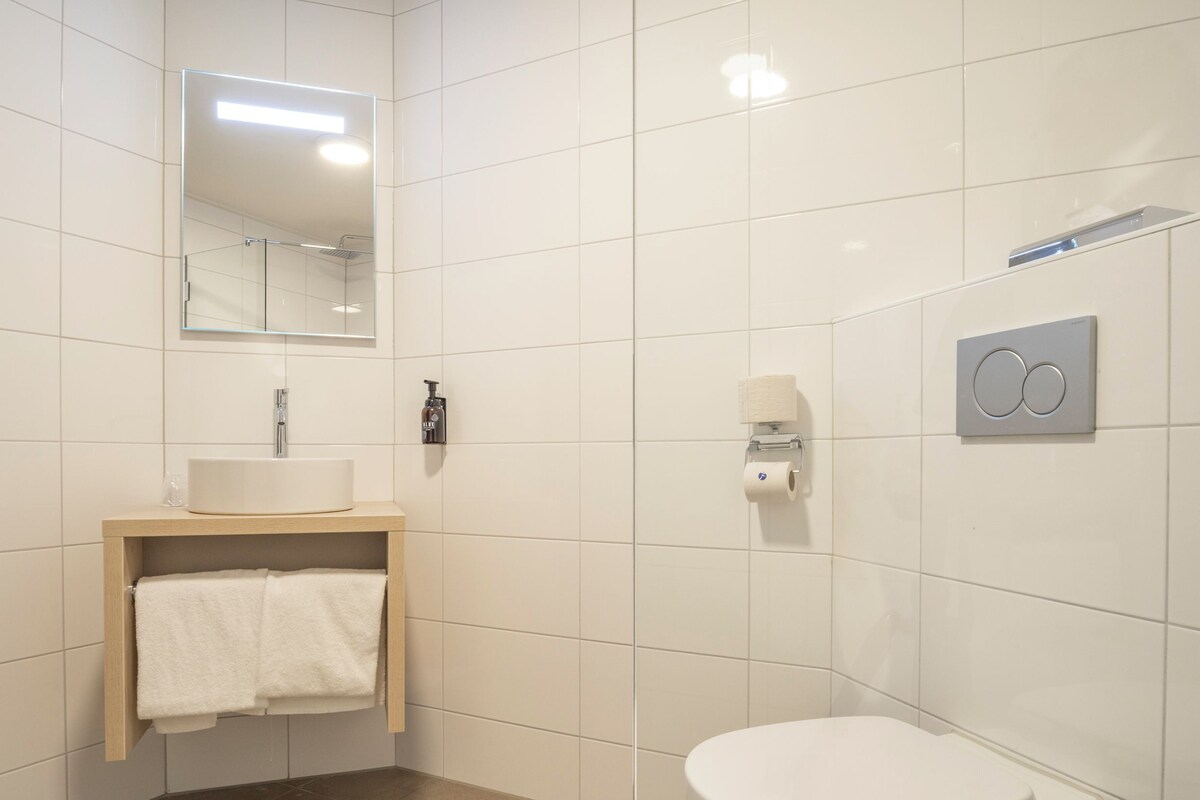 A modern bathroom with a white sink, mirror, and toilet.