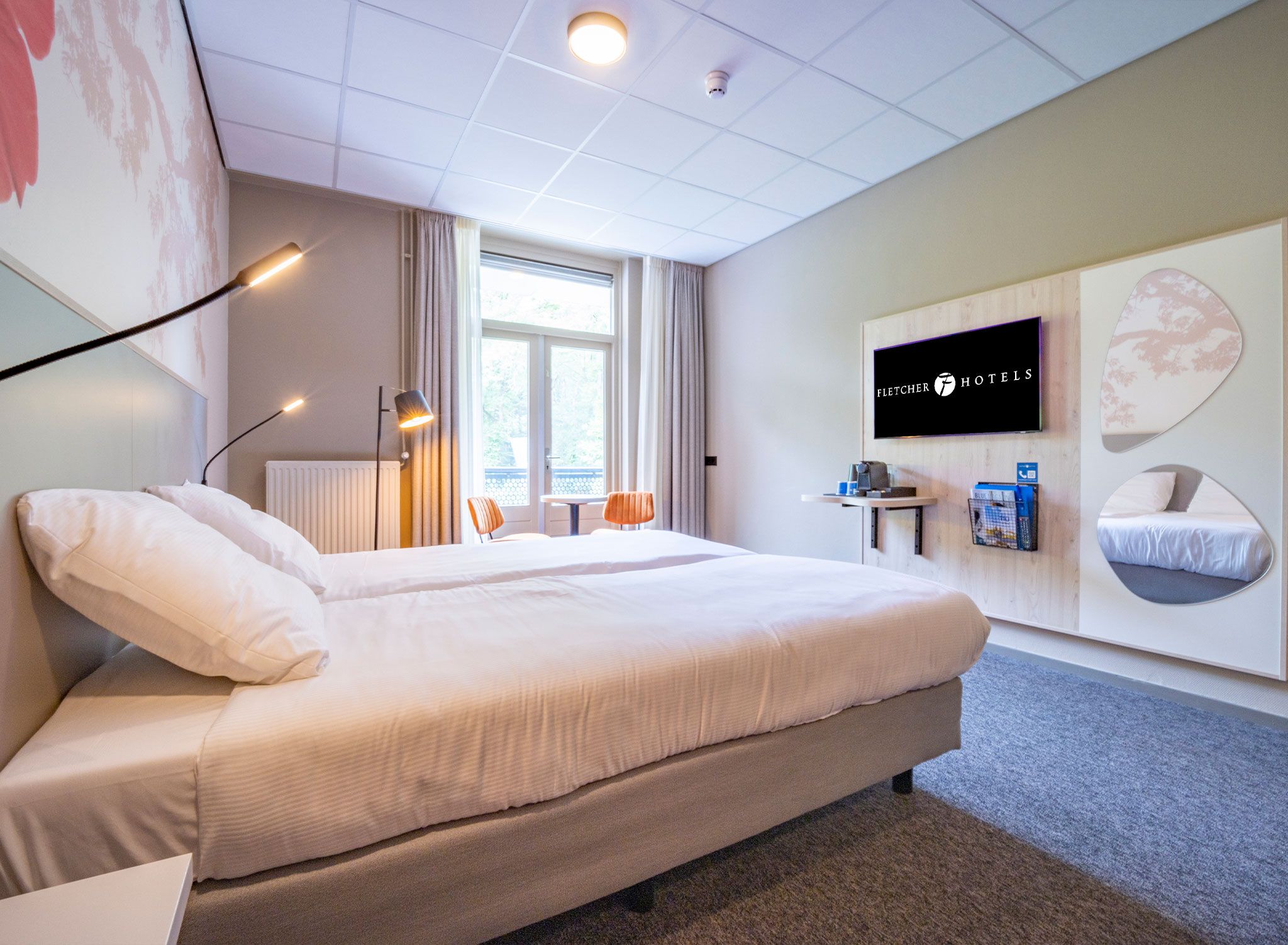A hotel room with a large bed, a desk, a chair, a TV, and a window.