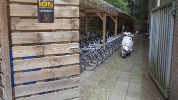 A wooden structure with a sign reading "ION ENERGY INSIDE opladpunt" and a row of bicycles and a scooter parked outside.