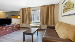 A modern living room with a flat-screen TV, wooden cabinet, sofa, and a window with curtains. - Extended Stay America Suites New York City LaGuardia Airport (Whitestone)