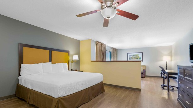 A hotel room with a large bed, a desk, a chair, a ceiling fan, and a television. - Extended Stay America Suites New York City LaGuardia Airport (Whitestone)