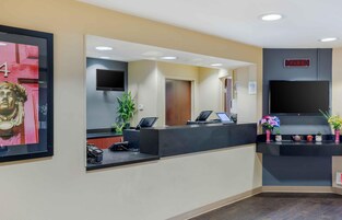 Un área de recepción con mostrador, televisor, detector de incendios y una obra de arte enmarcada.