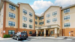 A multi-story hotel with a beige and brown facade, a lobby entrance, and a parking area. - Extended Stay America Suites New York City LaGuardia Airport (Whitestone)