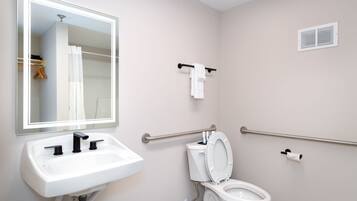 A bathroom with a white sink, a toilet, a mirror, and a towel rack.