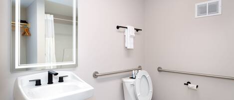 Un baño con un lavabo blanco, un inodoro, un espejo y un perchero para toallas.