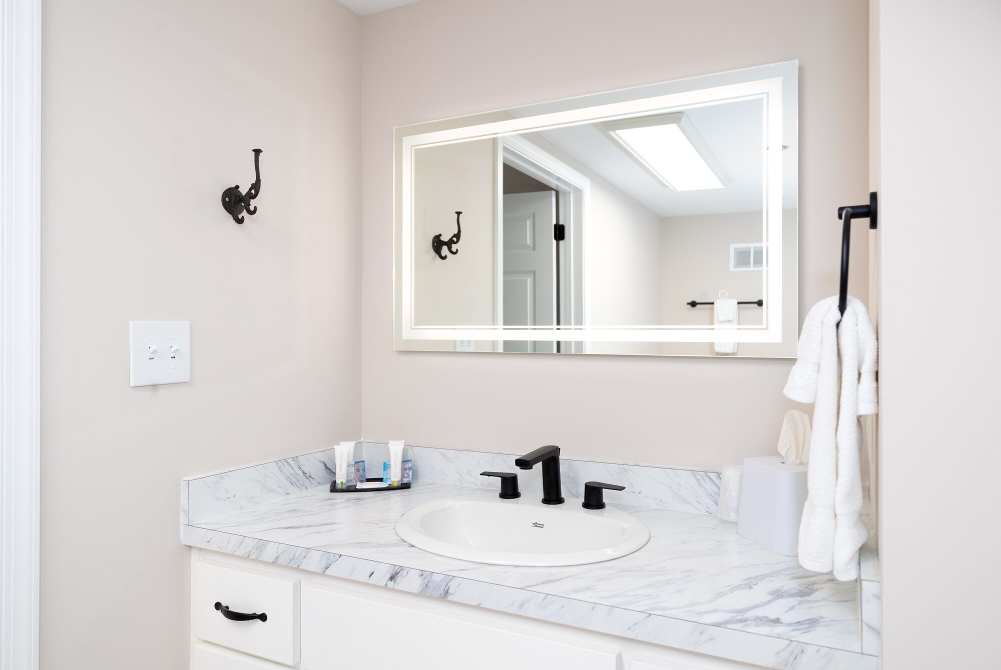 Een badkamer met een wit wastafel, een zwarte kraan en een grote spiegel.