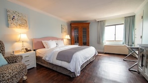 A bedroom with a bed, nightstands, a chair, a wardrobe, and a desk. - Bella Vista Hotel & Suites (Lynchburg)