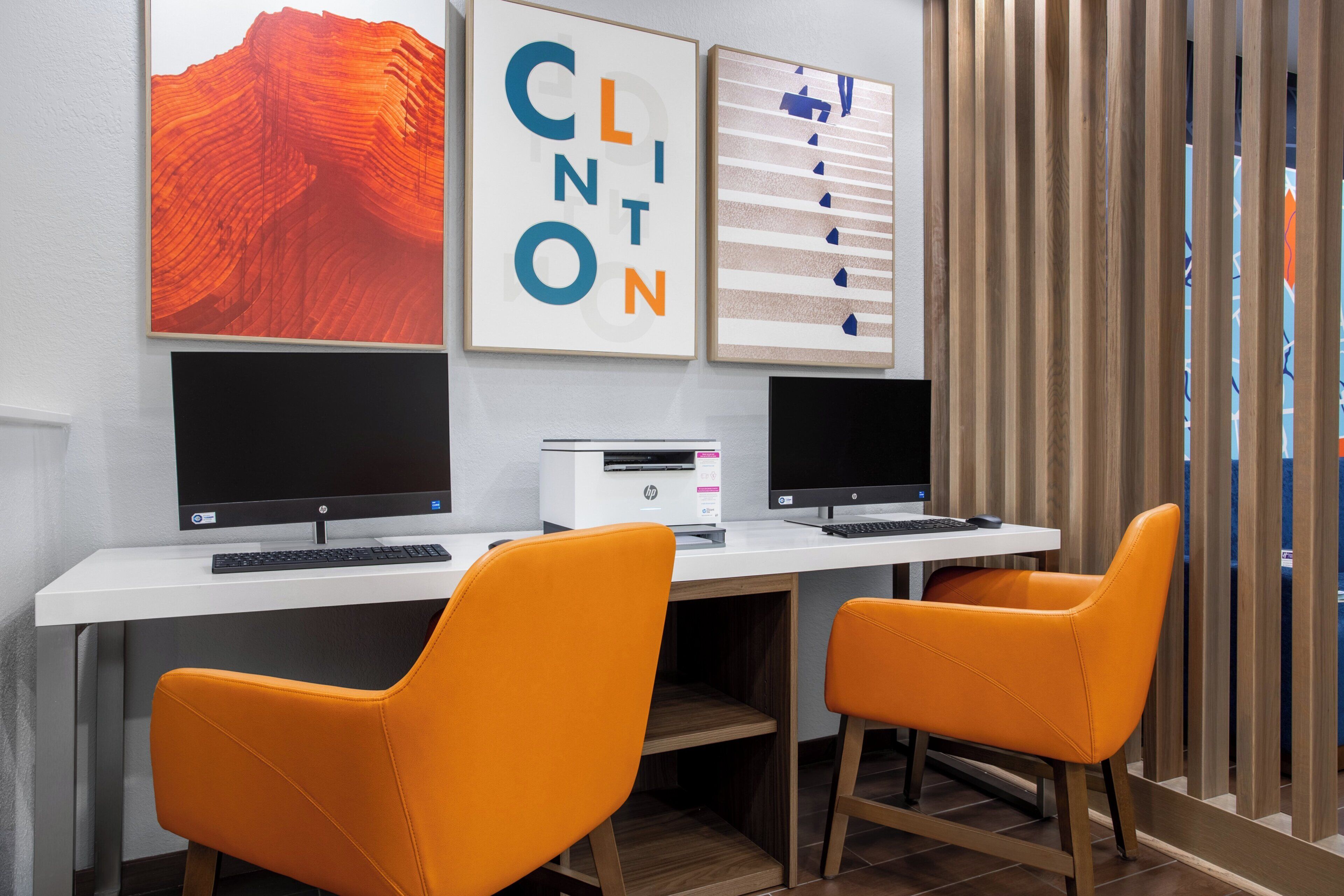 A workspace with two HP desktop computers, an HP printer, and two orange chairs.