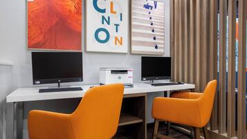 A workspace with two HP desktop computers, an HP printer, and two orange chairs.