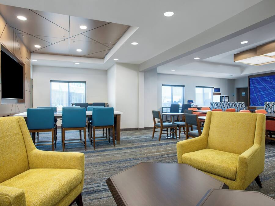 A hotel conference room with tables, chairs, and a large screen.