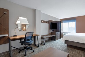 A hotel room with a bed, desk, chair, TV, and a large window.