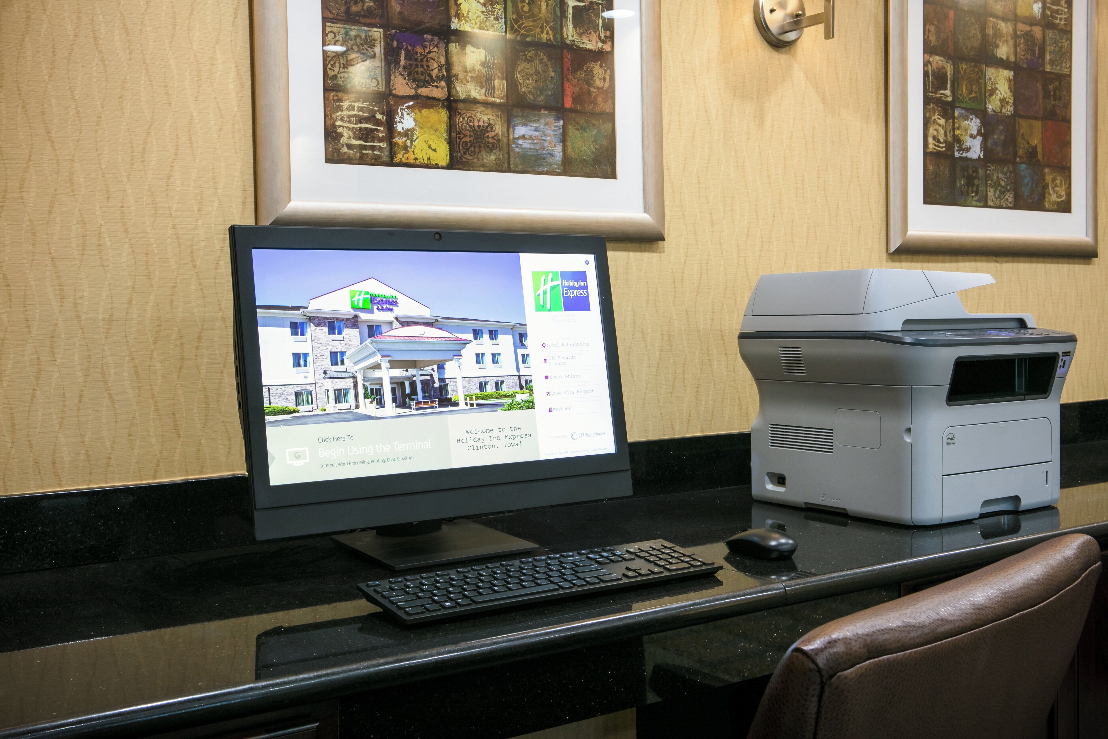 Un ordinateur de bureau avec un écran affichant le site web d’un hôtel, un clavier et une imprimante, le tout posé sur un bureau.