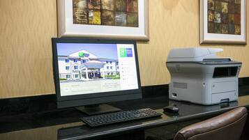 Un ordinateur de bureau avec un écran affichant le site web d’un hôtel, un clavier et une imprimante, le tout posé sur un bureau.