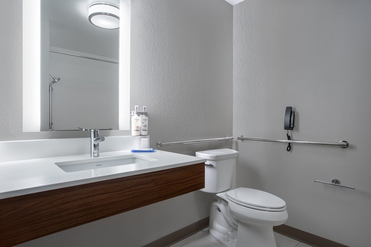 A modern bathroom with a white sink, a mirror, a toilet, and a shower.