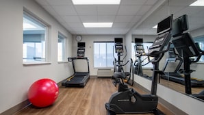 A gym with treadmills, an elliptical, a red exercise ball, and a clock on the wall. - Holiday Inn Express Hotel & Suites Clinton by IHG (Clinton)
