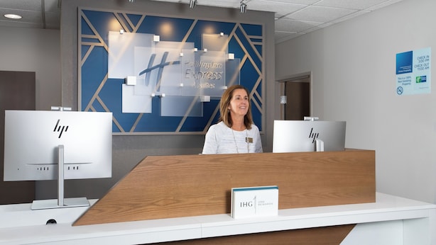 A reception desk with a sign reading "Holiday Inn Express & Suites" and "IHG ONE REWARDS". - Holiday Inn Express Hotel & Suites Clinton by IHG (Clinton)