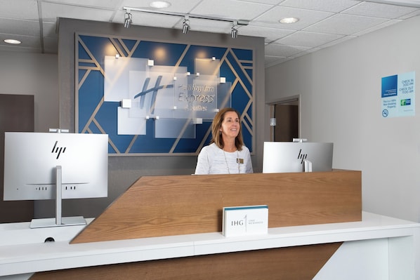 Un comptoir d’accueil avec une enseigne indiquant « Holiday Inn Express & Suites » et « IHG ONE REWARDS ».