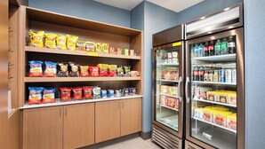 A snack and beverage display area with shelves stocked with various chips and a refrigerated section with bottled drinks.