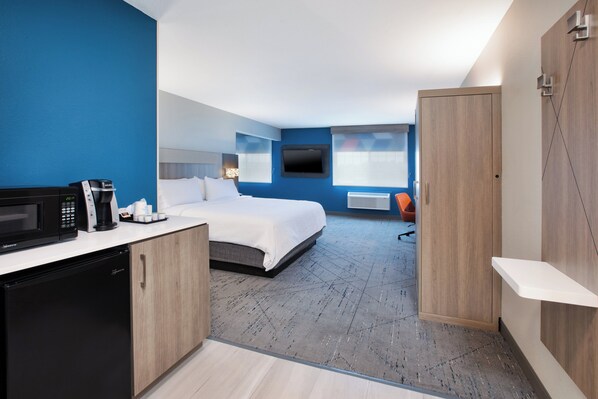 A modern hotel room with a bed, a desk with a microwave, a coffee maker, and a TV mounted on the wall. - Holiday Inn Express Hotel & Suites Defiance by IHG (Defiance)
