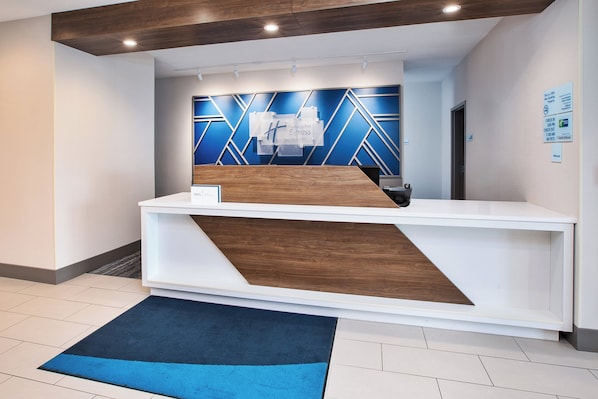 Un mostrador de recepción de diseño moderno, con detalles de madera y un cuadro mural geométrico azul.
