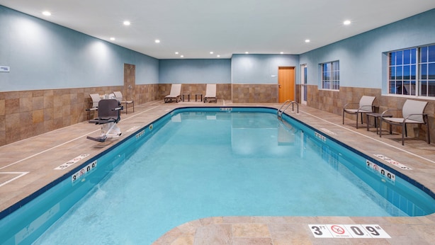 A swimming pool with a 3ft depth limit, lounge chairs, and a door leading to another room.