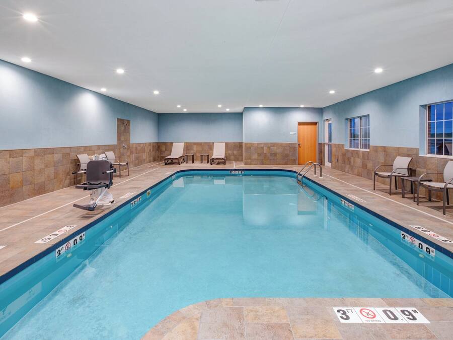 A swimming pool with a 3ft depth limit, lounge chairs, and a door leading to another room.