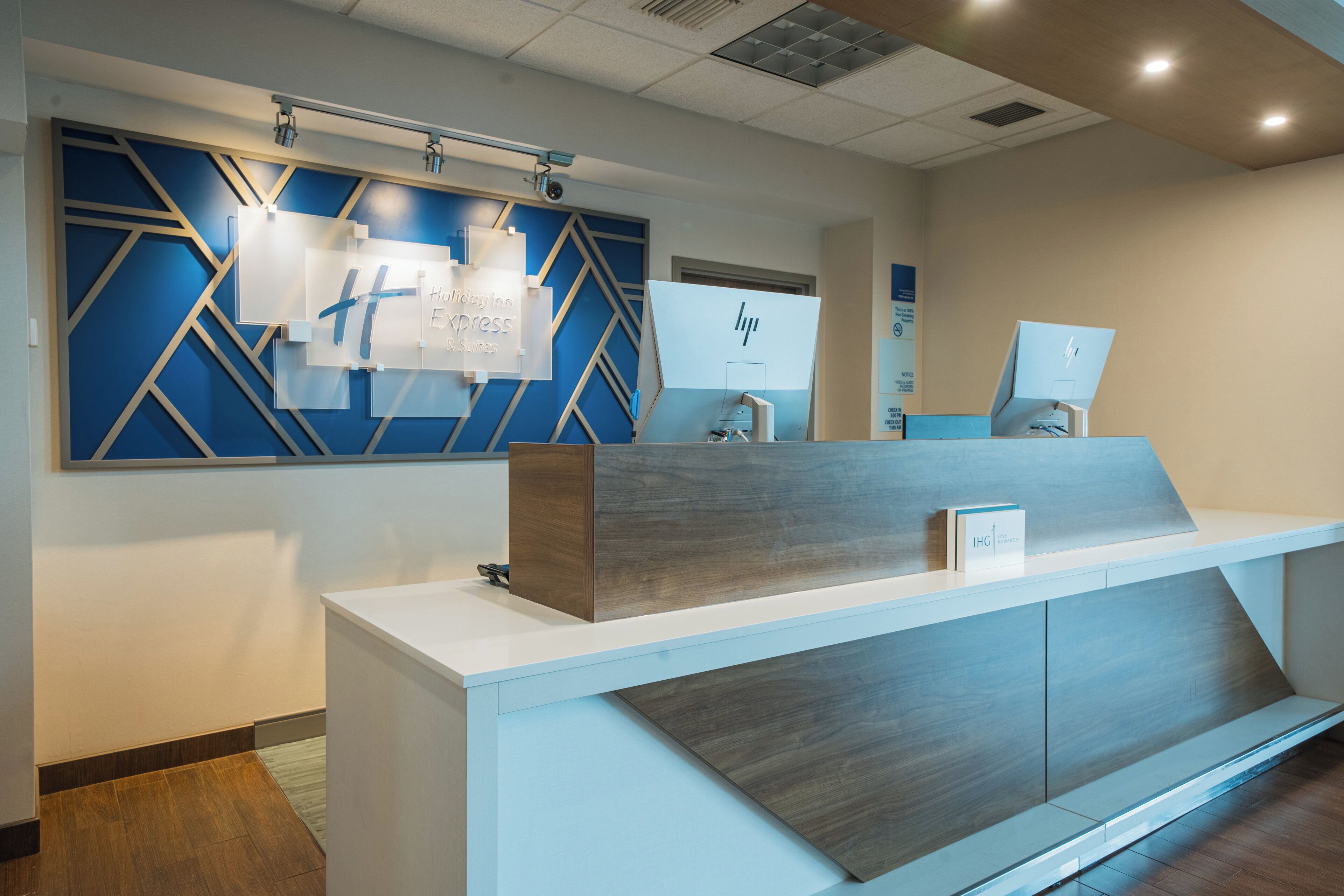 A reception desk with a modern design, a blue geometric wall pattern, and a sign indicating 'Holiday Inn Express'.