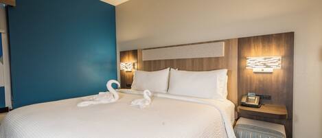 A hotel room with a large bed, two bedside lamps, a nightstand, and a wall-mounted phone.