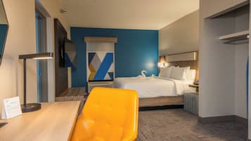 Una habitación de hotel con una cama, un escritorio, una silla y un televisor.