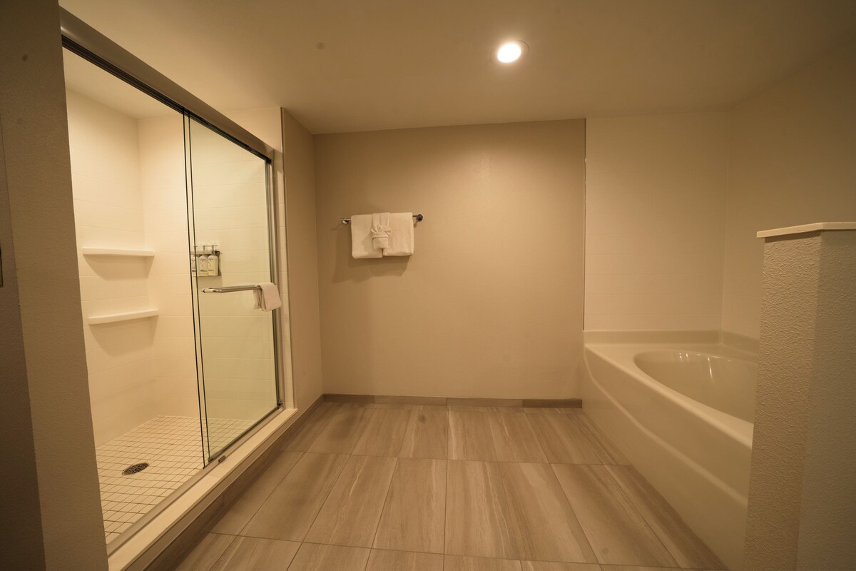 A bathroom with a glass-enclosed shower, a bathtub, and a tiled floor.