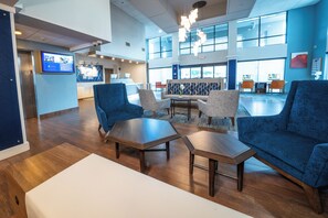 A spacious lobby with a reception desk, seating area, and a large window providing natural light. - Holiday Inn Express Hotel & Suites Tampa Northwest - Oldsmar by IHG (Oldsmar)