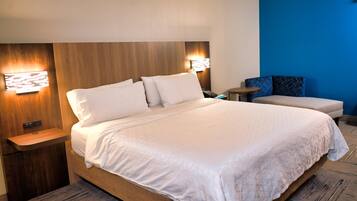 Quarto de hotel com uma cama grande, mesas de cabeceira, uma escrivaninha, uma cadeira e uma parede azul.