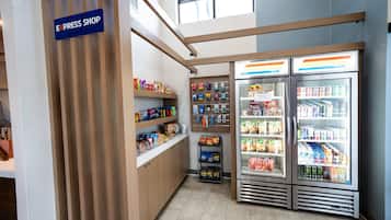A small express shop with shelves stocked with snacks and beverages, and two refrigerated display cases with drinks.