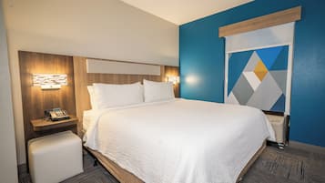 Ein Hotelzimmer mit einem großen Bett, Nachttischen, einer Wanduhr und einer Wanddekoration mit geometrischem Muster.