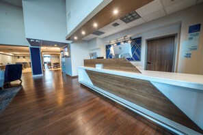 A modern reception area with a wooden reception desk, a blue accent wall, and a check-in counter.