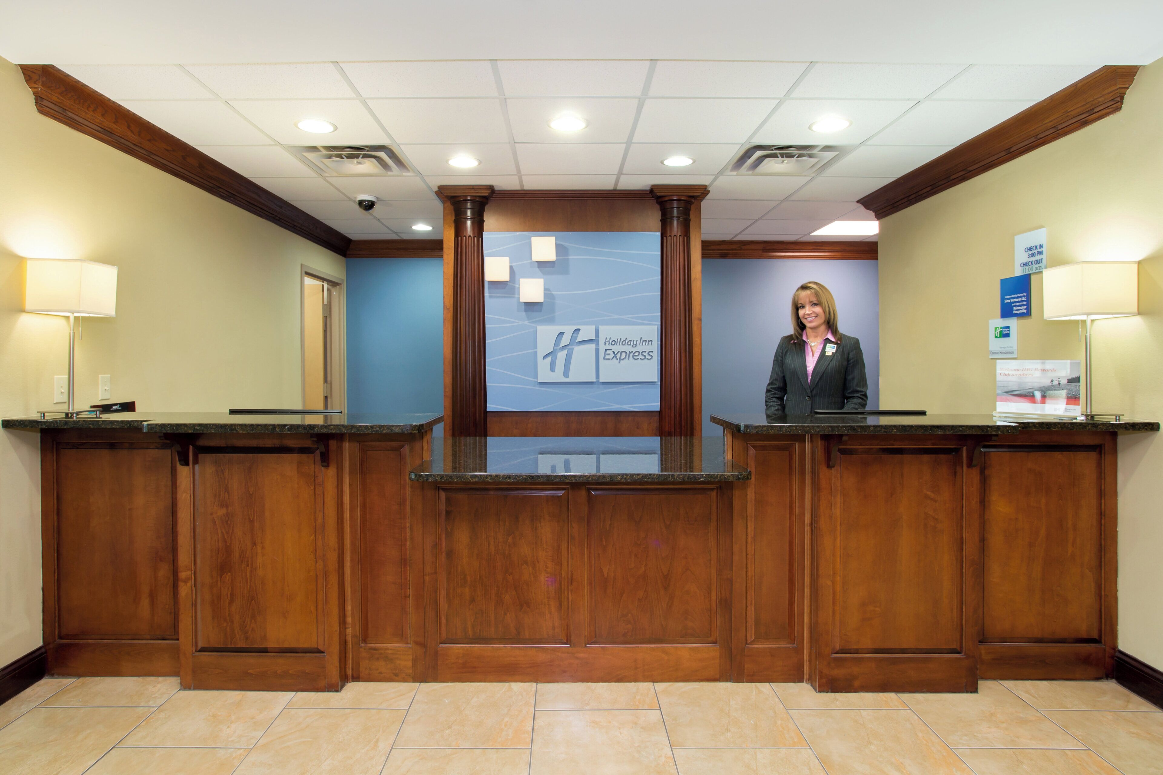 A reception desk with a wooden finish, a blue wall with a Holiday Inn Express sign, and a security camera on the ceiling.