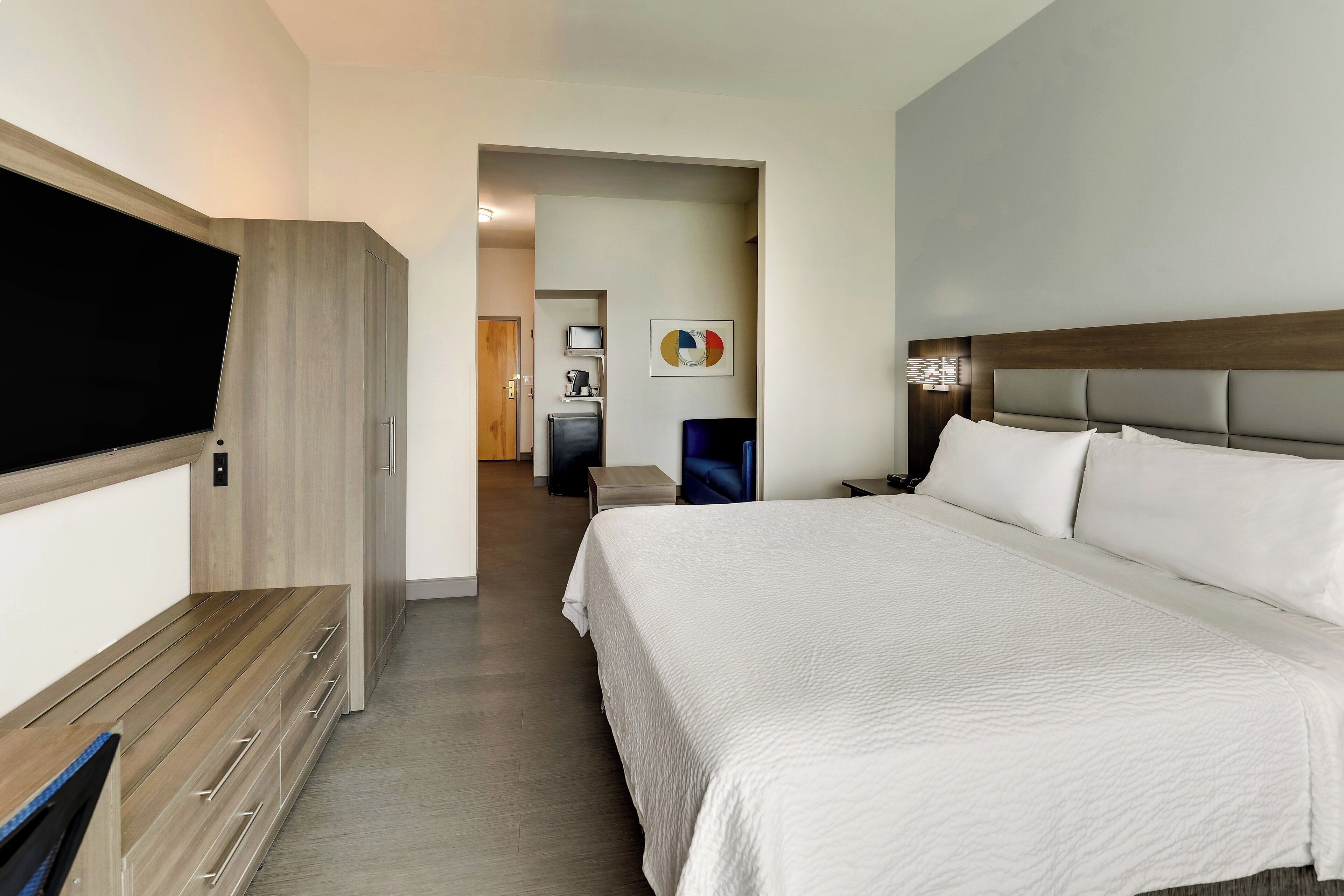 Habitación de hotel con cama, escritorio, armario y televisión.