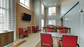 A conference room with a large table, red chairs, and a flat-screen TV mounted on the wall.