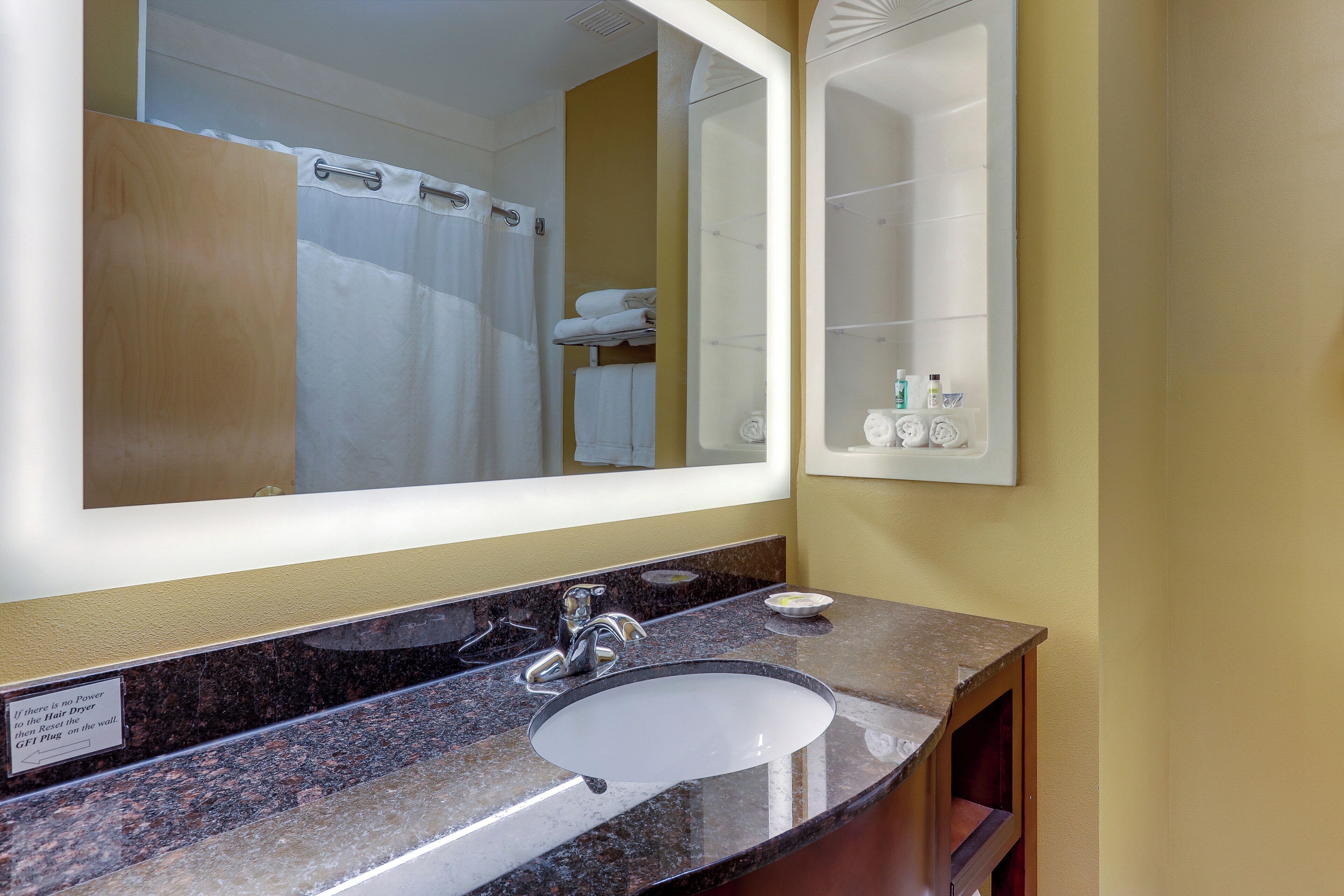 A bathroom with a large mirror, a sink, and a towel rack.