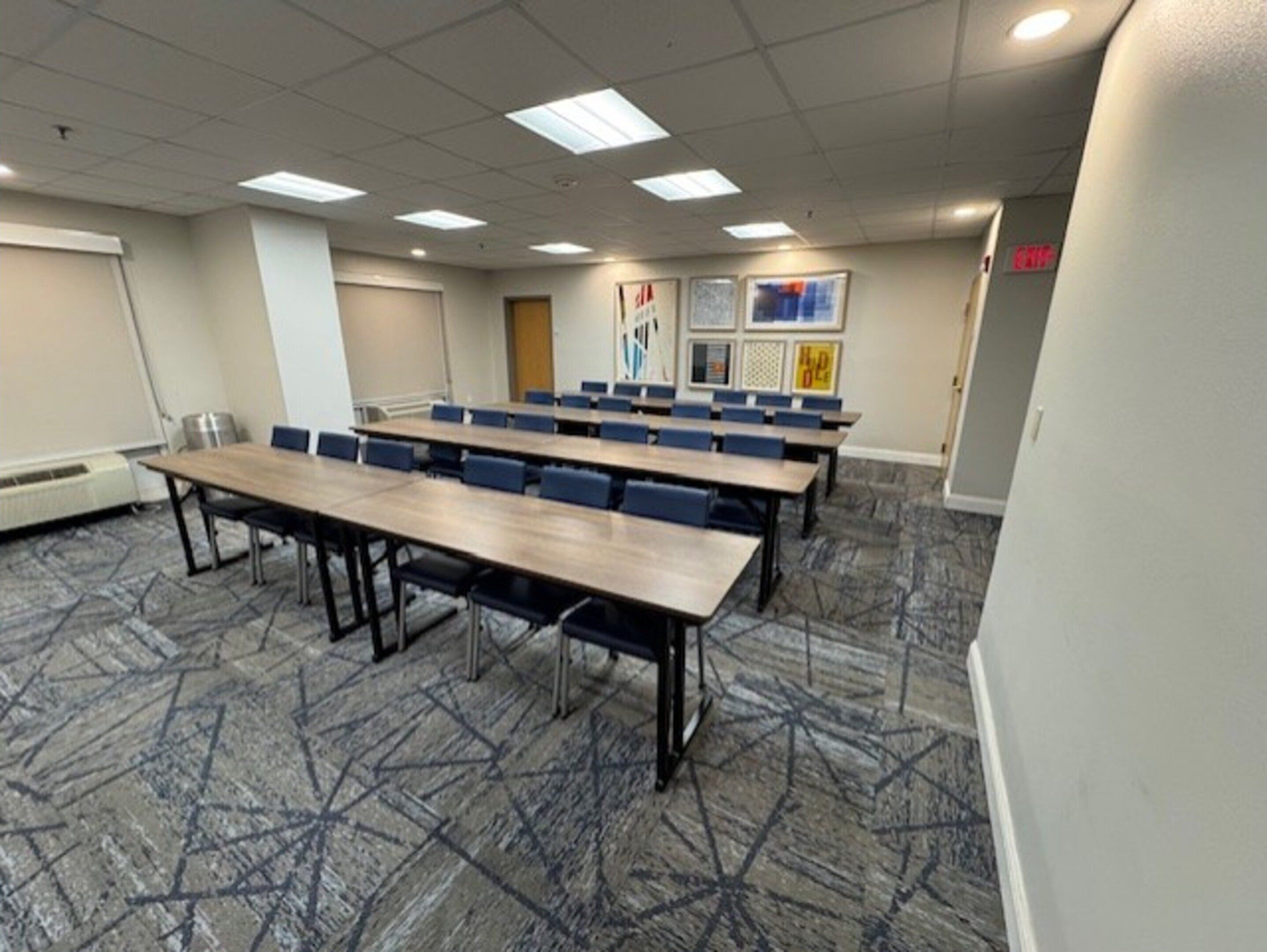 A conference room with long tables and chairs, a whiteboard, and framed pictures on the wall.