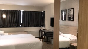 Una habitación de hotel con dos camas, un escritorio, una silla, un televisor y un espejo grande.