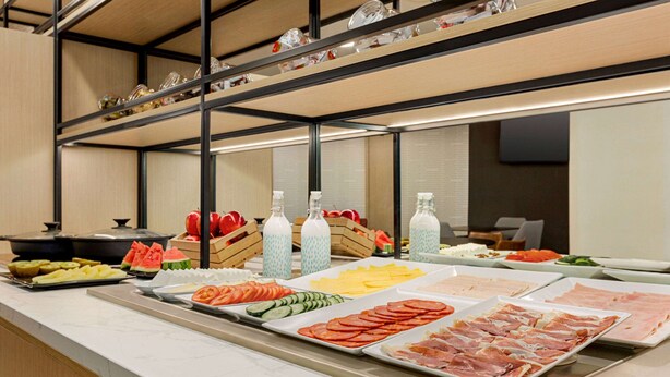 Un bufé con diferentes opciones de comida, incluyendo frutas, verduras y carnes.