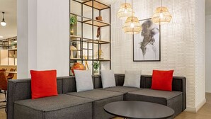 Una sala de estar moderna con un sofá seccional, una mesa de centro redonda y una estantería empotrada con adornos.