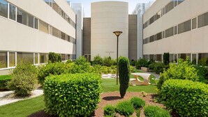Un patio con una farola en el centro, rodeado de setos bien cuidados y una pequeña zona de jardín.