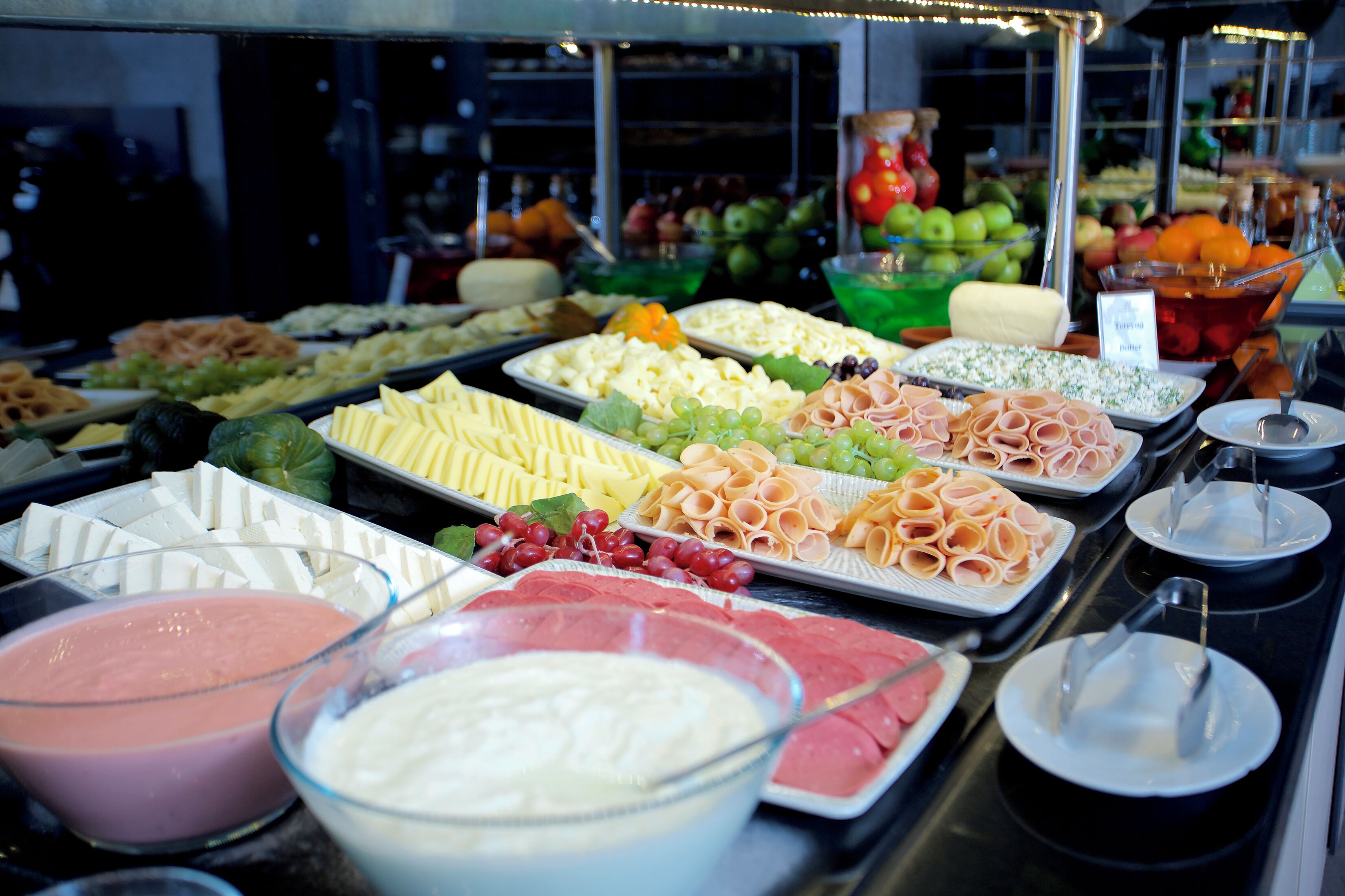 A buffet with various food items including cheeses, meats, and fruits.
