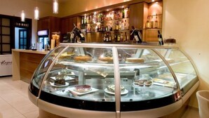 A dessert display case in a restaurant with a variety of pastries and cakes. - Crystal City Hotel (Athens)